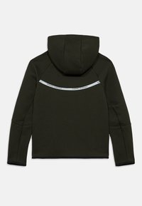 Φούτερ με κουκούλα σε ελιά πράσινο χρώμα με λεία υφή, διαθέτει ανακλαστική ταινία και λογότυπο Nike Tech στην πλάτη. Μακριά μανίκια, αθλητική εφαρμογή.