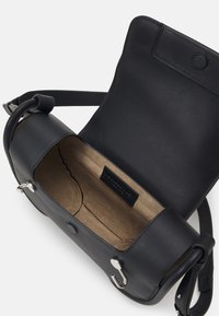Borsa a tracolla in pelle nera con una forma arrotondata, dotata di chiusura a scatto e accessori in argento. L'interno è in suede beige con etichetta del marchio.