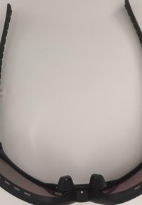 Czarne sportowe okulary przeciwsłoneczne z opływowymi ciemnymi szkłami i regulowanymi noskami na białej powierzchni.