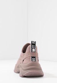 Baskets tricotées roses avec une semelle texturée, une languette de tirage présentant un logo noir et blanc, et un col rembourré pour le confort.