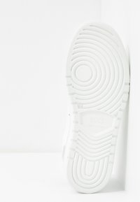 Semelle de chaussure de sport blanche avec des motifs circulaires et ondulés, présentant une finition texturée et un détail de logo en relief. Fabriquée en Italie.