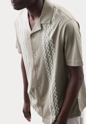 Short-sleeve, beige shirt with a collared design, featuring a vertical chain pattern in light blue and a button-down front.