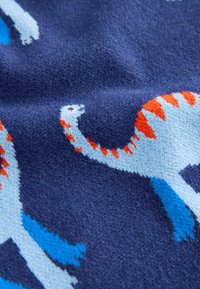 Modrá pletená tkanina s motívom štýlizovaných dinosaurov v svetlomodrej a oranžovej farbe na tmavomodrom pozadí, vyznačujúca sa jemnou textúrou a živými farbami.