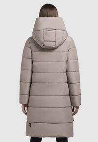 Light beige puffer coat with a high collar and hood, featuring horizontal quilted design, long sleeves, and logo patch at the hem.