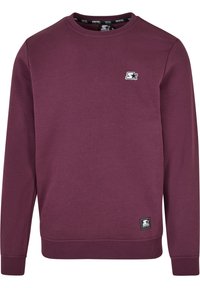 Sudadera de cuello redondo de manga larga en color púrpura oscuro con pequeños logotipos de estrellas en negro y blanco en el pecho y el dobladillo.