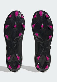 Musta urheilukengän pohja, jossa on geometrisia kuvioita, pinkkejä kolmioita, sekä karhea pinta pitävyyden parantamiseksi.