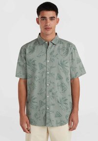 Korte mouwen button-up shirt in lichtgroene stof met een patroon van vissen, palmbladeren en driehoeken in donkerdere groentinten.