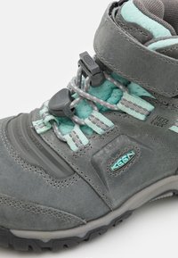 Grauer Wanderschuh mit strukturiertem Obermaterial, mintgrünen Schnürsenkeln und einem befestigten Riemen. Verfügt über eine Gummisohle für Halt und Flexibilität.