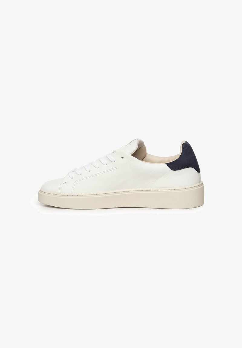 Zapatilla de cuero blanca con puntera redondeada, cordones blancos y suela baja de plataforma beige. Acento en azul marino oscuro en el talón. Textura suave en toda la superficie.