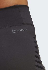 Mustad mustad spordileggingud tekstuurse viimistlusega, millel on "AEROREADY" logo ja külgedel lõigatud triibud ventilatsiooni jaoks.