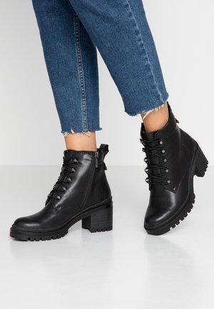 Black leather ankle boots with a chunky heel, lace-up front, and side zipper. Features textured rubber sole and looped pull tab.