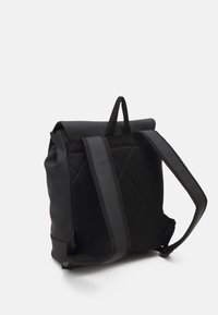 Zaino nero con un esterno liscio, texture trapuntata sul retro e spallacci imbottiti e regolabili per il massimo comfort.