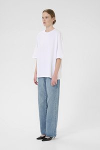 Tricou alb supradimensionat din bumbac, cu mâneci scurte, asociat cu blugi largi de culoare albastru deschis �și pantofi cu vârf ascuțit de culoare neagră.