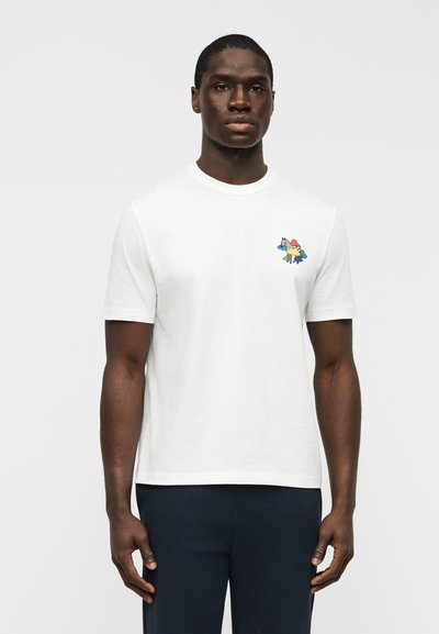 Λευκό βαμβακερό T-shirt με μικρό πολύχρωμο γραφικό στην αριστερή πλευρά του στήθους. Κοντά μανίκια, στρογγυλή λαιμόκοψη και άνετη εφαρμογή.