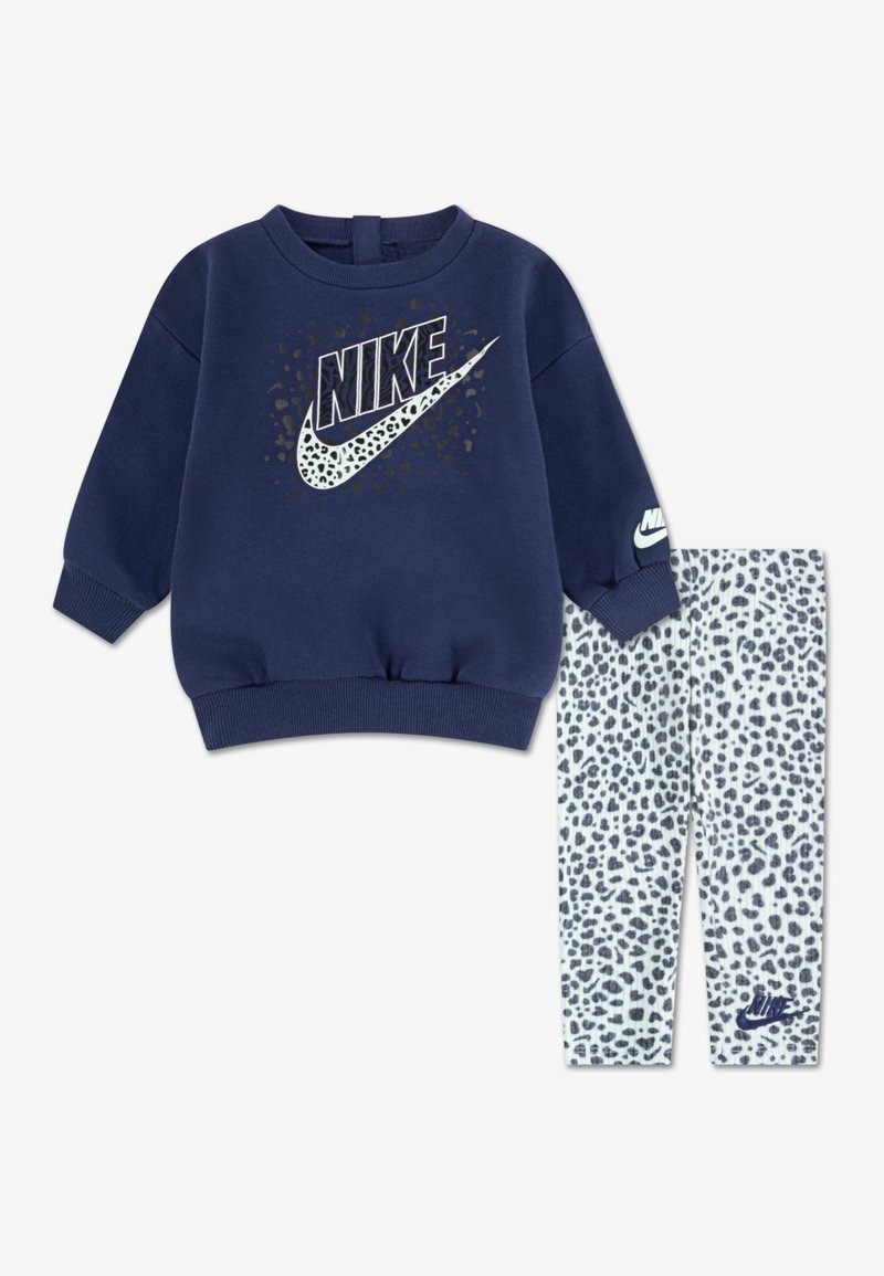 Granatowy sweatshirt z wyraźnym logo Nike, w komplecie z legginsami w biały, teksturowany wzór w panterkę oraz małym logo.