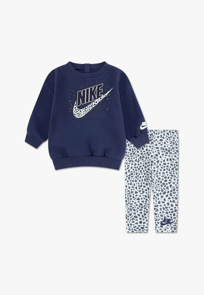 Granatowy sweatshirt z wyraźnym logo Nike, w komplecie z legginsami w biały, teksturowany wzór w panterkę oraz małym logo.