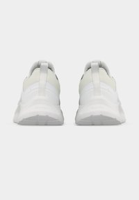 Ζευγάρι λευκά αθλητικά παπούτσια, ορατά από πίσω, με θηλιές και υφασμένα πέλματα σε απλό φόντο.