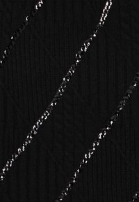 Schwarzer, texturierter Stoff mit diagonalen Linien aus glänzenden schwarzen Pailletten, die einen Kontrast zur gerippten Strickoberfläche bilden.