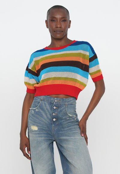 Multicolored knitted crop sweater with red ribbed hem, featuring horizontal stripes in blue, green, orange, and brown; paired with high-waisted denim jeans.