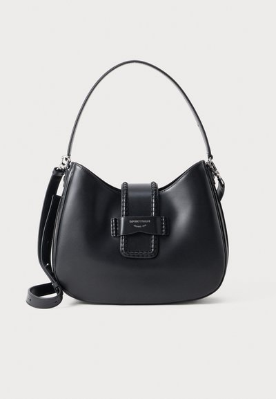 Bolso de hombro de cuero negro con forma curva, un mango trenzado y un cierre prominente. Cuenta con una correa desmontable y herrajes metálicos.