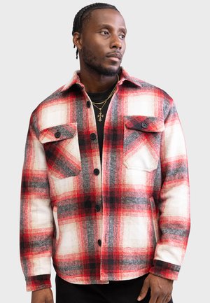 Rood en zwart geruite flanellen shirt met witte accenten, voorzien van twee borstzakken, een knoopsluiting aan de voorkant en een standaard kraag. Gek textureerde stof.