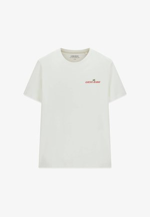 Weißes T-Shirt mit kurzen Ärmeln und Rundhalsausschnitt, mit kleinem "GUESS JEANS"-Schriftzug und grünem Palmenlogo auf der linken Brust.