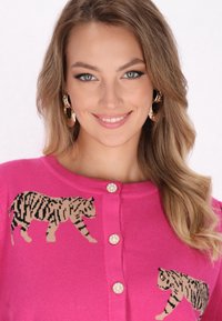 Rožinė megzta kardigano striukė su dviem juodais ir smėliniais tigro motyvais, puošta keturiais dekoratyviais perlų mygtukais priekyje.