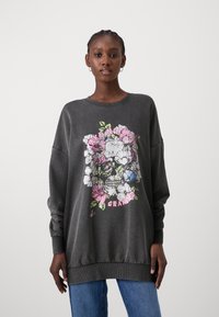 Dark grey sweatshirt with a crew neck and oversized fit, featuring a colorful floral skull graphic on the front and ribbed cuffs.