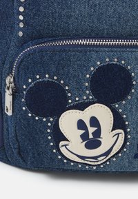 Plecak dżinsowy z dużą naszywką Mikiego Mouse'a w kolorze kremowym i granatowym, ozdobiony srebrnymi ćwiekami oraz kieszonką na zamek.