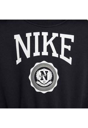 Felpa nera con grande lettering bianco "NIKE" e un logo circolare con "N" e il testo "EST. 72," inserito in un distintivo argento testurizzato.