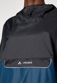 Vodoodporen Vaude pončo v črni in modri barvi. Ima visok ovratnik, nastavljivo vrvice in logotip na sprednji strani. Gladka tekstura.