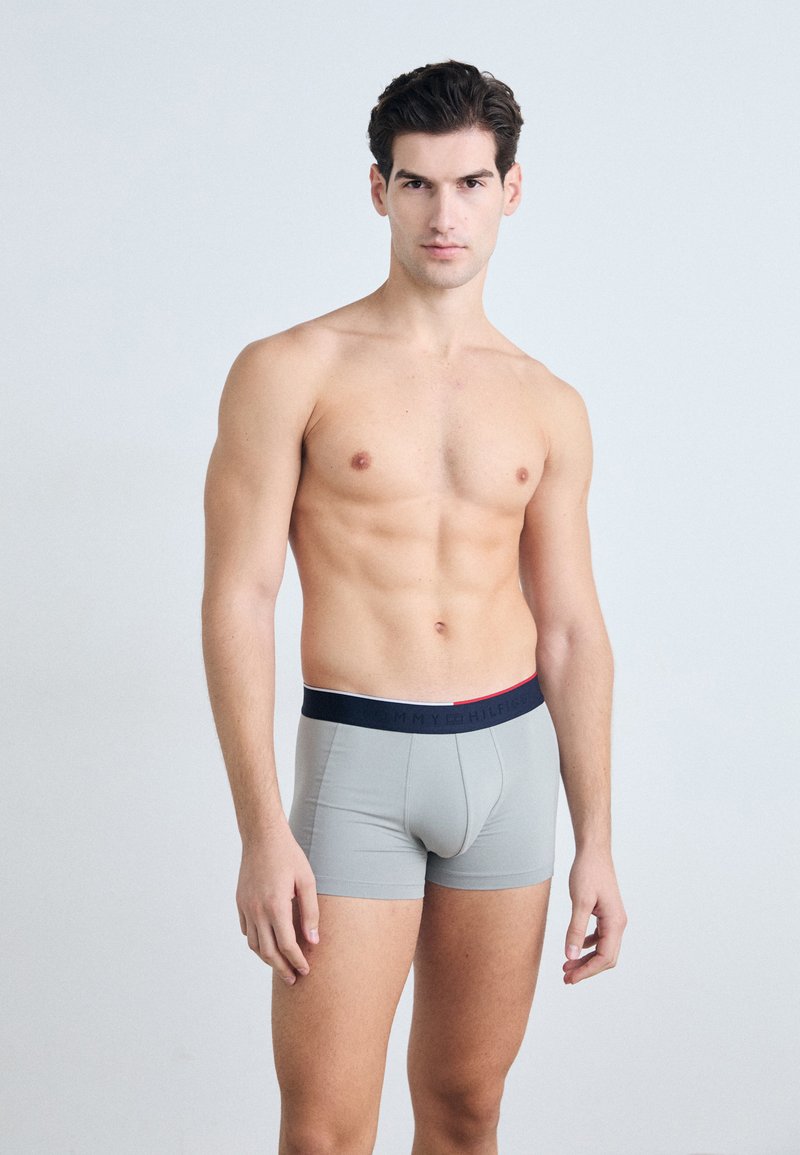 Boxer briefs grigi con elastico blu navy con strisce rosse e bianche, realizzati in un materiale liscio ed elastico, design aderente.