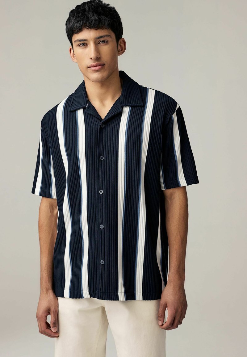 Camisa de manga corta con cuello, con rayas verticales en azul marino y blanco, tela texturizada y cierre de botones en el frente.