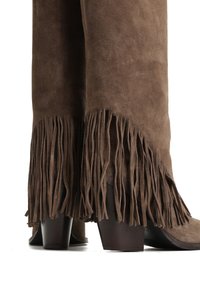 Brązowe zamszowe botki do kostki z frędzlami na brzegu i drewnianym obcasem typu klocka, eksponujące fakturę i unikalny design.