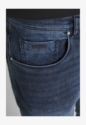Dunkelblaue Jeansrückseite mit einer kleinen schwarzen Etikette mit der Aufschrift "Antony Morato", die oberhalb der Tasche aufgenäht ist.