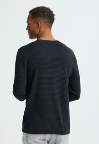 Donker gestreept shirt met lange mouwen van gestructureerde stof, met een ronde halslijn en een klein accentdetail aan de zoom.