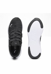Scarpe da ginnastica Puma in bianco e nero, una mostra la parte superiore con i lacci, l'altra mostra la suola con i pattern di presa e il logo Puma.