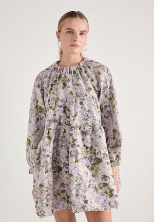 Robe florale avec des manches bouffantes, comportant un col froncé. Couleurs violet clair et vert avec un motif de grandes roses sur l'ensemble.