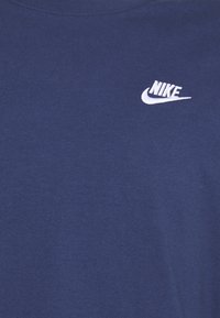Mörkblå bomullströja med en liten vit broderad Nike-logga på bröstet. Klassisk rundhalsdesign och mjuk textur.