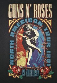 Sort t-shirt med et vintage grafisk tryk af en danser i blå og rød, omgivet af pigtråd og roser, med teksten "GUNS N' ROSES".
