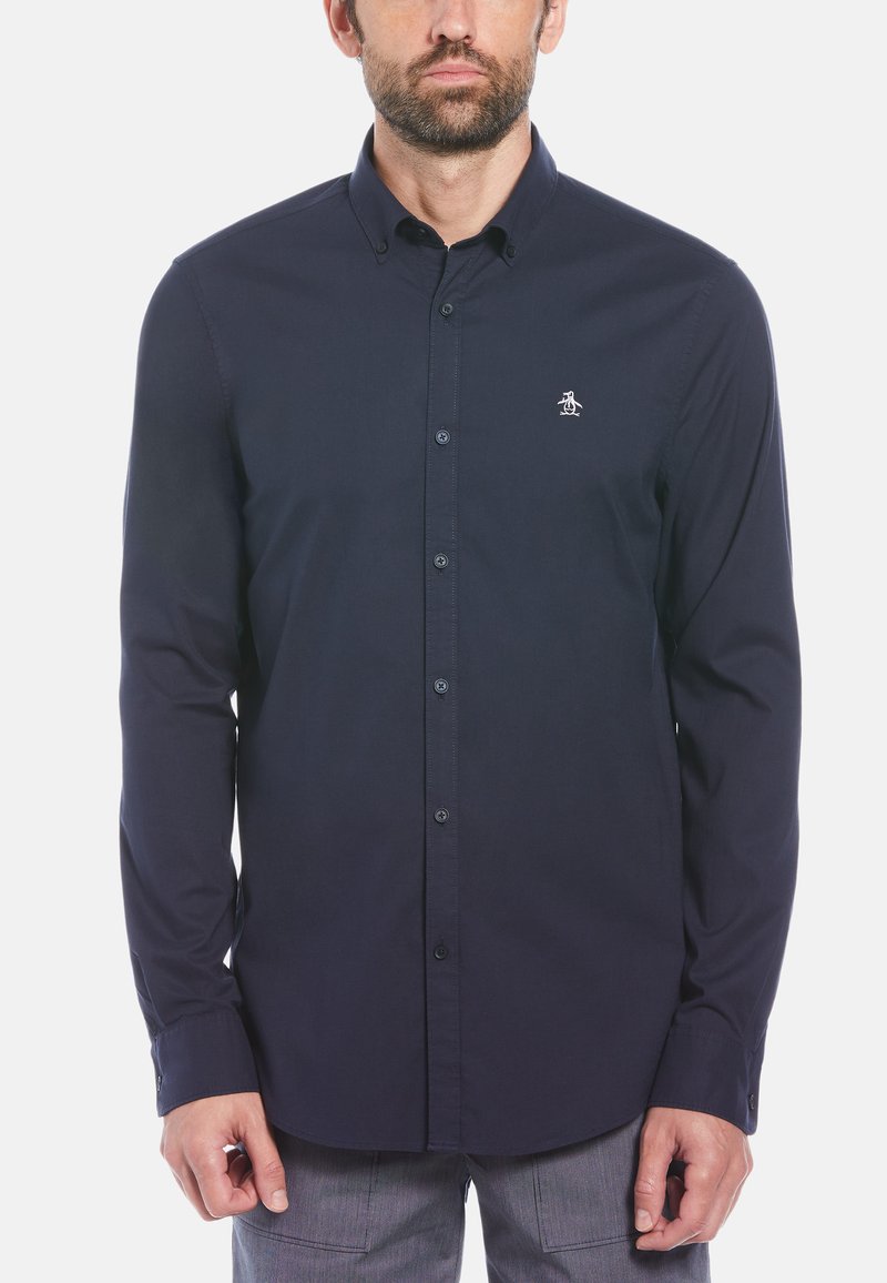 Navyblauwe lange mouwen shirt met een button-down kraag, voorzien van een klein wit logo op de linkerkant van de borst en bijpassende knopen. Dichte stoftextuur.