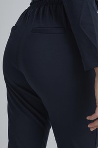 Dunkelblaue Jogginghosen mit elastischem Bund und Gesäßtaschen, aus einem glatten Stoff gefertigt, mit einem figurschmeichelnden Design und subtiler Textur.