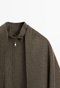 Dark grey wool cape with a high collar, featuring a single button closure and a zippered front, showcasing soft, textured fabric.