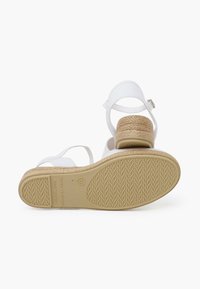 Valged sandaalid espadrille-stiilis kiilkontsaga, millel on tekstuuriga pruuni värvi tald, reguleeritav pahkluu rihm ja minimalistlik disain.
