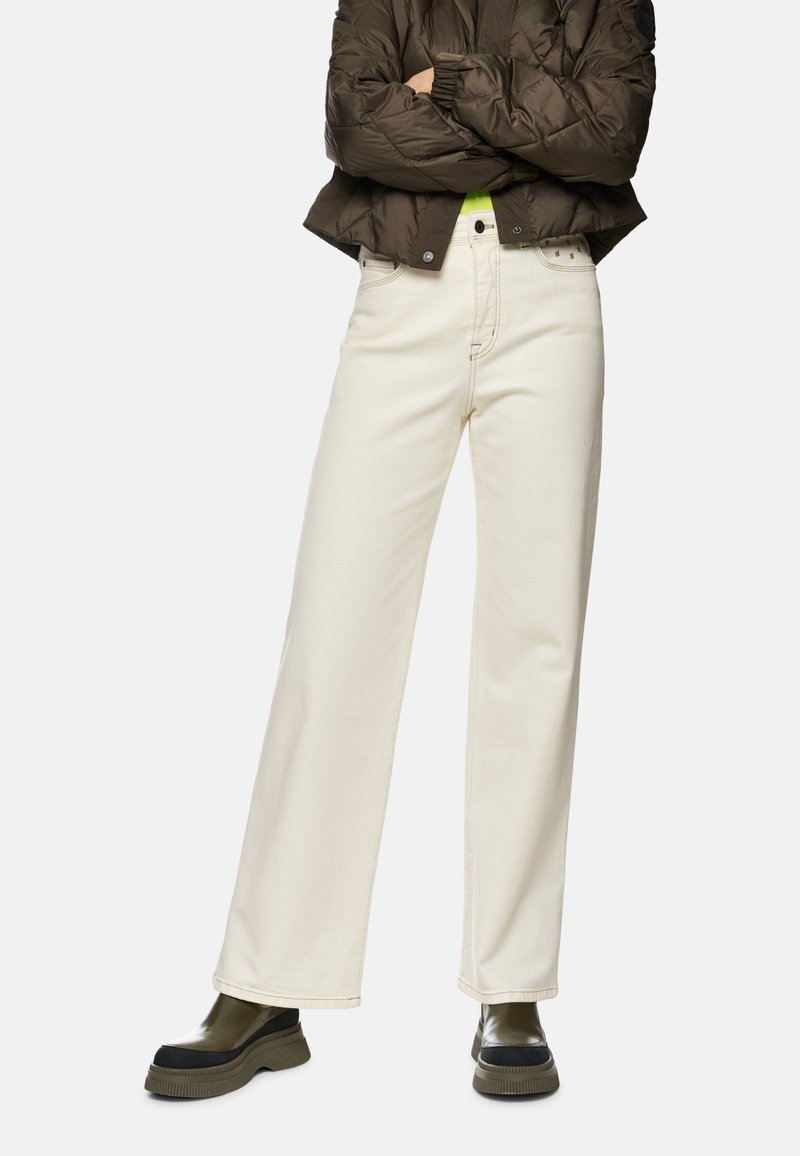 Wide-leg white denim pants with a high waist, featuring a front button fly, and subtle stitching details. Paired with an olive green puffer jacket.