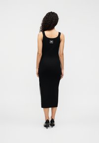 Μαύρο αμάνικο midi φόρεμα με εφαρμοστή γραμμή, πλαϊνή σχισμή και λογότυπο στο πίσω μέρος. Λεία υφή και ύφασμα με ελαφριά γυαλάδα.
