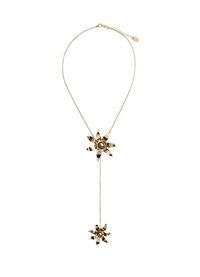 Colier din metal auriu, prezentând două ornamentații florale; una mai mare în partea de sus și una mai mică dedesubt. Designul lanțului are modele intricate pe fiecare floare.