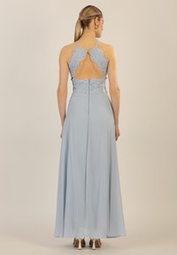 Lyseblå kjole med en svævende nederdel, blonde detaljer på ryggen og en udskæringsdetalje. Stoffet har en blød tekstur og er let.