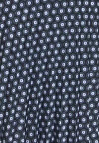 Černá tkanina s opakujícím se květinovým vzorem v světle modré a bílé, obsahující malé květiny obklopené kruhovými akcenty. Hladká textura.