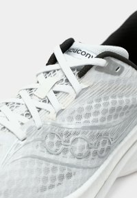 Close-up of a white Saucony running shoe with mesh upper, crisscrossed laces, and signature logo on the side.